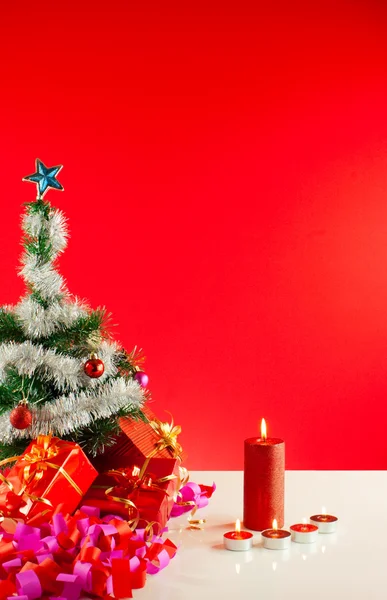 Weihnachtsgeschenke mit Kerzen auf rotem Hintergrund — Stockfoto