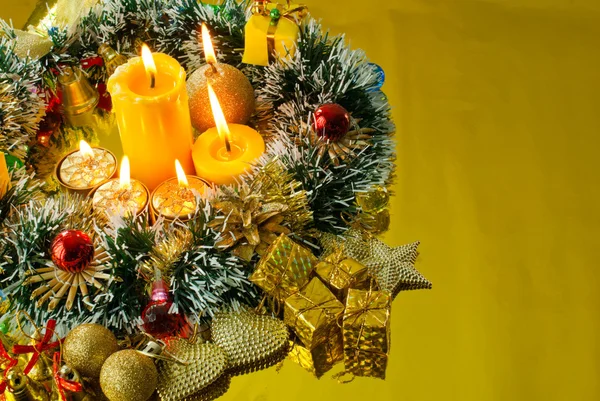 Noel çelenk ve yanan mum altın arka plan üzerinde — Stok fotoğraf