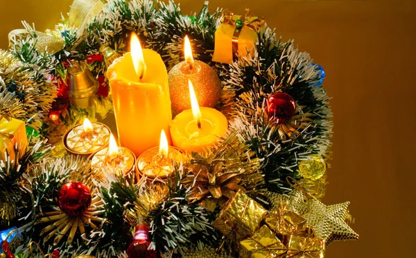 Noel çelenk ve yanan mum altın arka plan üzerinde — Stok fotoğraf