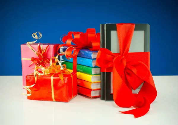 Kerstcadeautjes met elektronische boek lezer tegen blauwe achtergrond — Stockfoto
