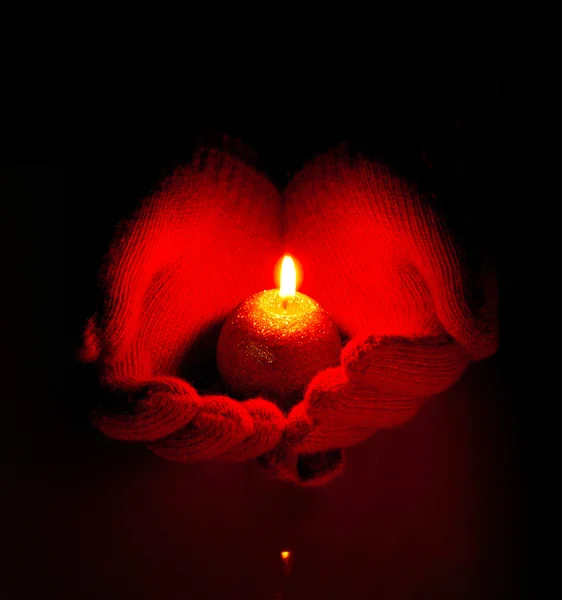 Las manos humanas sostienen la vela encendida contra fondo oscuro — Foto de Stock