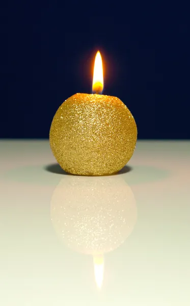 Golden burning candle against blue background — Stock Photo, Image