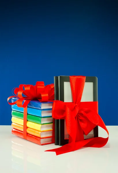 Boeken vastgebonden met lint en elektronische boek lezer tegen blauwe pagina — Stockfoto