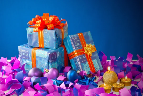 Weihnachtsgeschenke und Kerzen auf blauem Hintergrund — Stockfoto