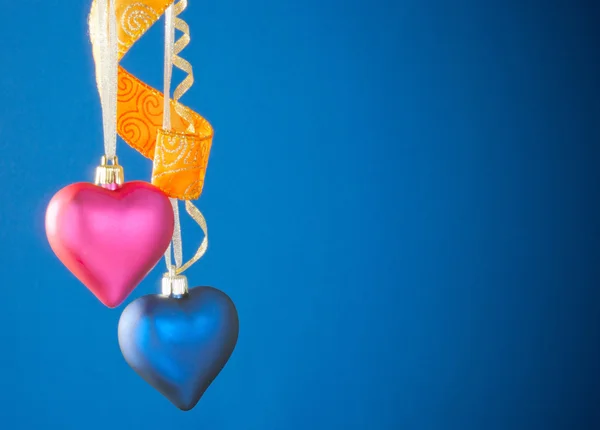 Dois brinquedos em forma de coração pendurados contra fundo azul — Fotografia de Stock