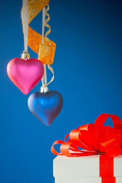 Due giocattoli a forma di cuore appesi sullo sfondo blu — Foto Stock