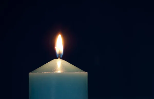 Fechar a vela acesa contra fundo azul escuro — Fotografia de Stock