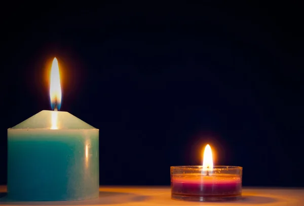 Dwie świece przed ciemnym niebieskim tle — Zdjęcie stockowe
