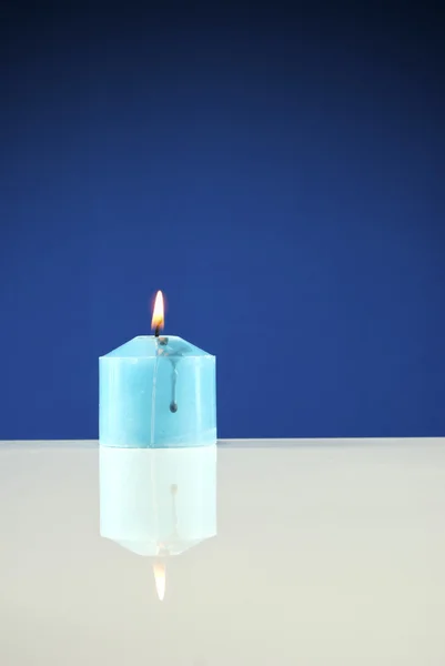 Detailní záběr hořící svíčka tmavě modré pozadí — Stock fotografie