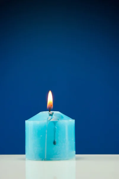 Detailní záběr hořící svíčka tmavě modré pozadí — Stock fotografie