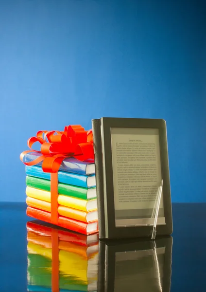 Empilement de livres avec lecteur de livres électroniques sur fond bleu — Photo