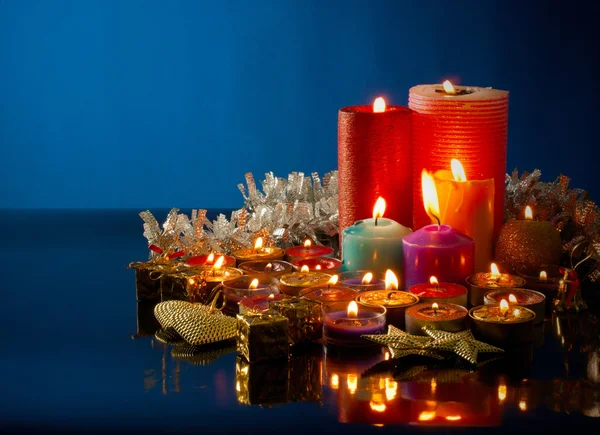 Una gran cantidad de velas de colores ardientes contra fondo azul oscuro — Foto de Stock