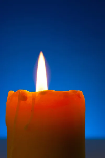 Zblízka hořící svíčky proti modré pozadí — Stock fotografie