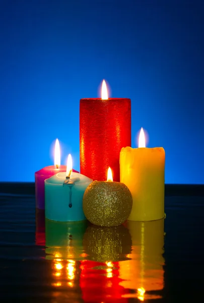 Cinco velas coloridas acesas contra fundo azul — Fotografia de Stock