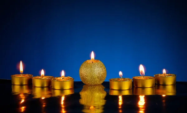 蓝色背景上的七个灼烧的蜡烛 — 图库照片