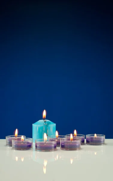 Um monte de velas acesas contra fundo azul escuro — Fotografia de Stock