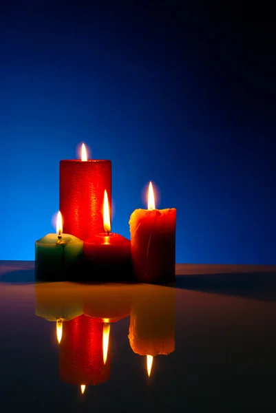 Vier brandende kleurrijke kaarsen tegen zwarte achtergrond — Stockfoto