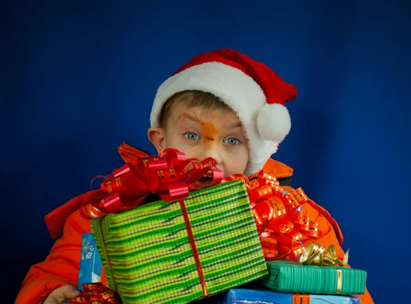Chico sorprendido mirando detrás de los regalos de Navidad — Foto de Stock