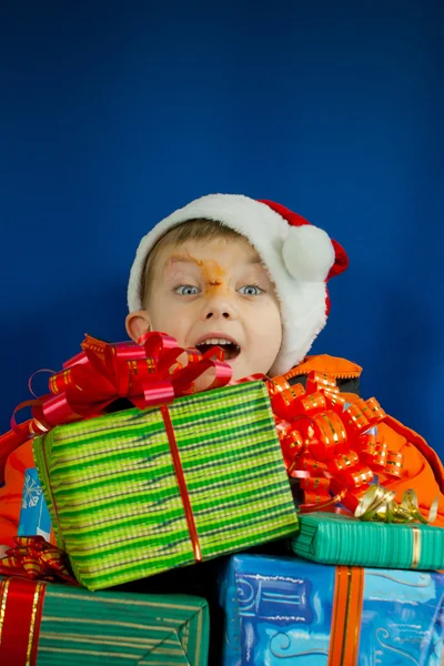 Surprised boy looking from behind the Christmas presents — Stock Photo, Image