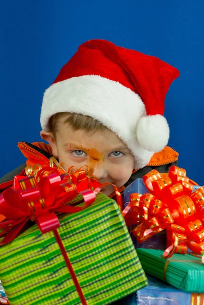 Chico sorprendido mirando detrás de los regalos de Navidad — Foto de Stock
