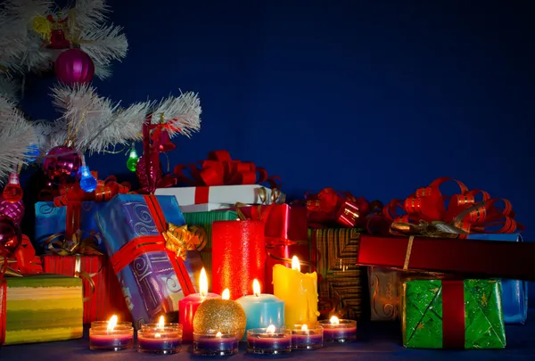 Noel hediyeleri ve mavi arka plana karşı yanan mumlar — Stok fotoğraf
