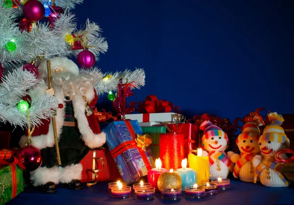 Três bonecos de neve na frente dos presentes de Natal e lata ardente — Fotografia de Stock