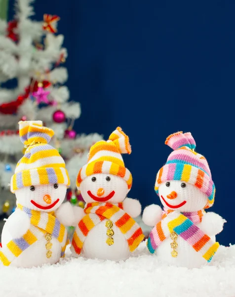 Tres muñecos de nieve en frente de la arboleda blanca siempre verde decorada — Foto de Stock