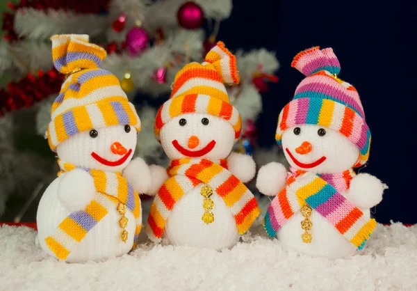 Três bonecos de neve na frente da ove árvore verde branca decorada — Fotografia de Stock