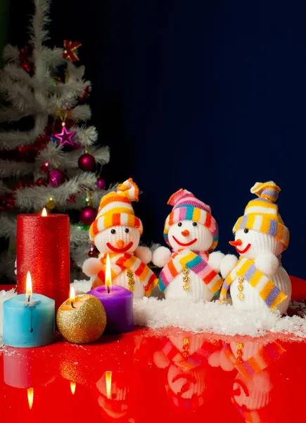 Три снеговика и горящие свечи на голубом фоне — стоковое фото