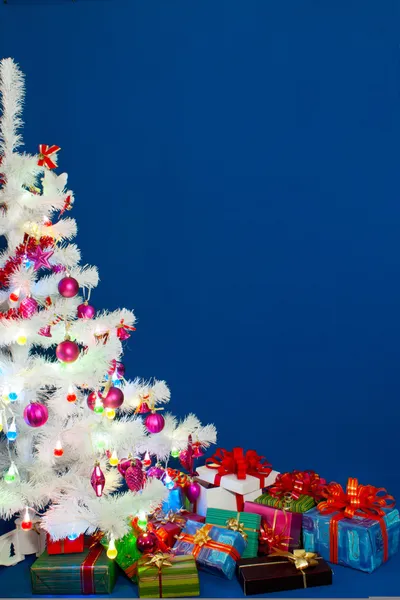 Haufen der Weihnachtsgeschenke unter geschmückten weißen immergrünen T — Stockfoto