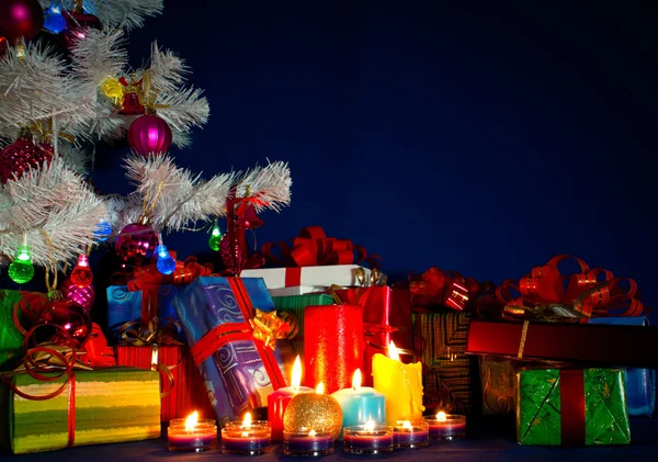 Noel hediyeleri ve mavi arka plana karşı yanan mumlar — Stok fotoğraf
