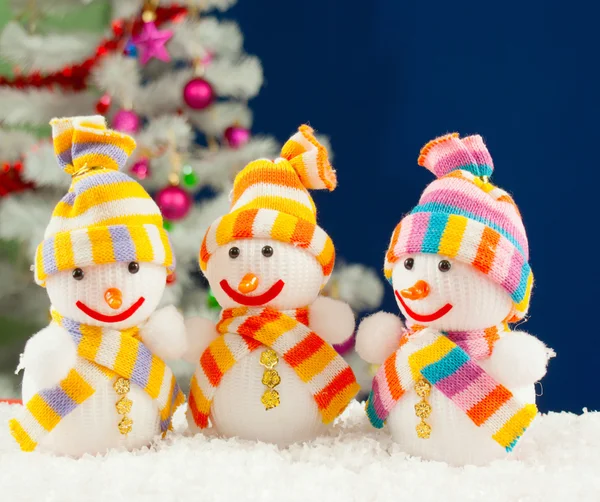 Three snowmen in front of the decorated white evergreen tree ove — Stock Photo, Image