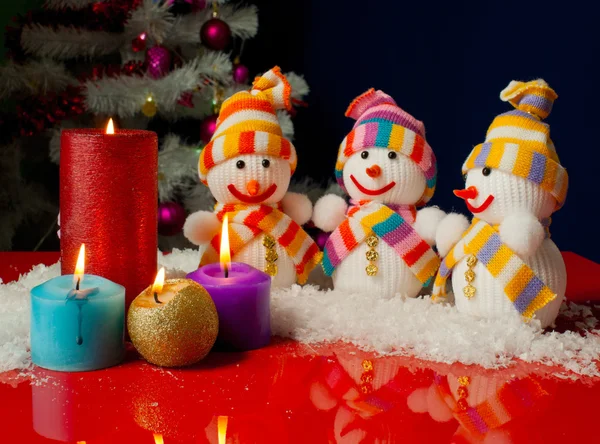 Три снеговика и горящие свечи на голубом фоне — стоковое фото