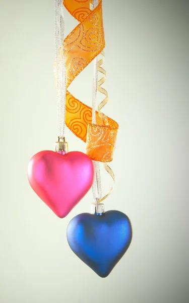 Dois brinquedos em forma de coração pendurados contra fundo leve — Fotografia de Stock