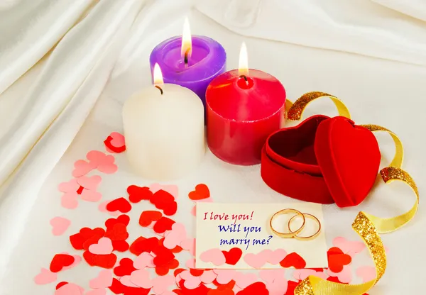 Dwa pierścienie i karty z propozycję małżeństwa z trzy świece — Zdjęcie stockowe