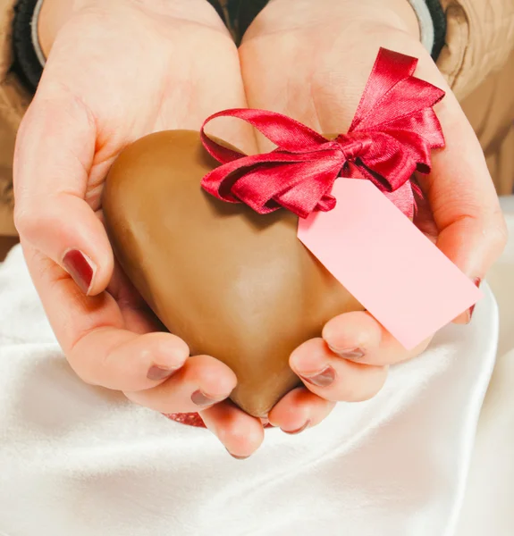 Hands holding a heart shaped chocolate candy — Stock Photo, Image
