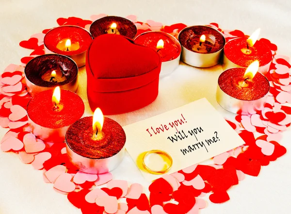 Кольцо и карточка с предложением руки и сердца со свечами — стоковое фото