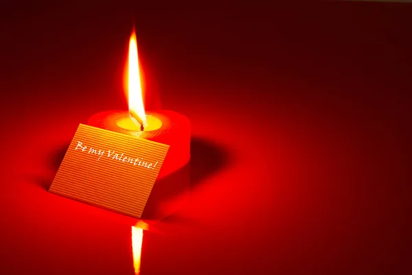 Vela en forma de corazón ardiente y una tarjeta de San Valentín —  Fotos de Stock