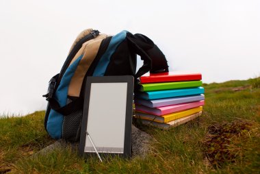 Stack of colorful books and electronic book reader clipart