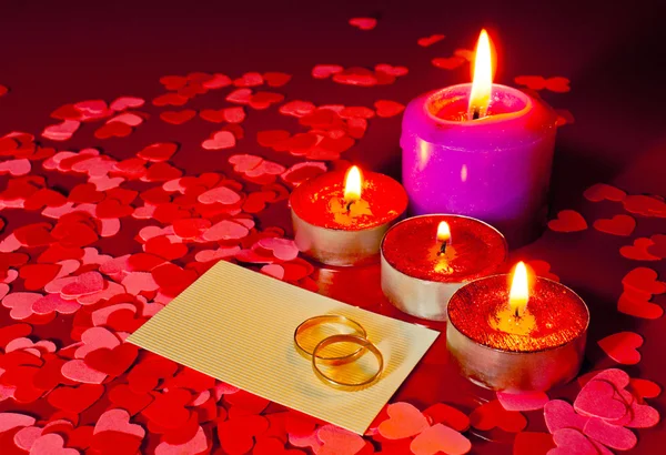 Dwa pierścienie i karty z propozycję małżeństwa z cztery świece — Zdjęcie stockowe