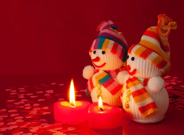 Two snowmen with two burning heart shaped candles — Stock Photo, Image