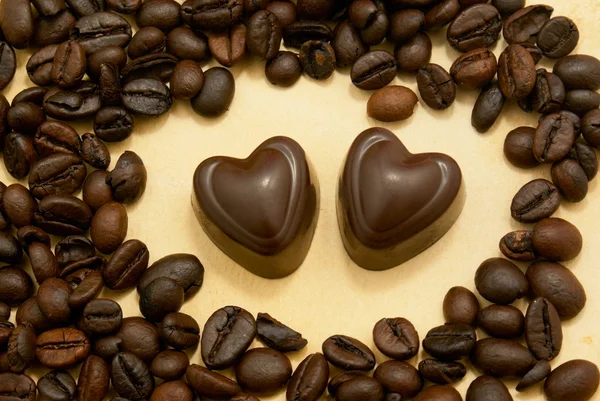 Două bomboane de ciocolată în formă de inimă și boabe de cafea — Fotografie, imagine de stoc