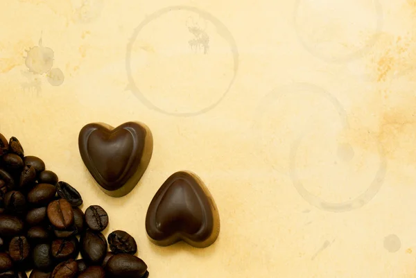 Dois doces de chocolate em forma de coração e grãos de café — Fotografia de Stock