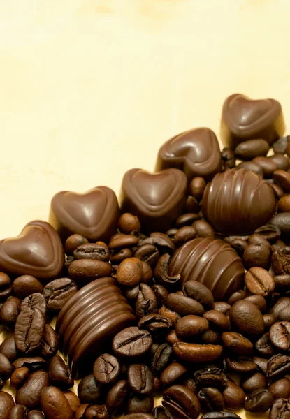 Doces de chocolate em forma de coração e grãos de café — Fotografia de Stock