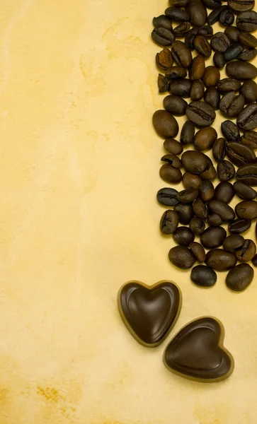 Dvě srdce tvaru čokoládové bonbony a kávová zrna — Stock fotografie