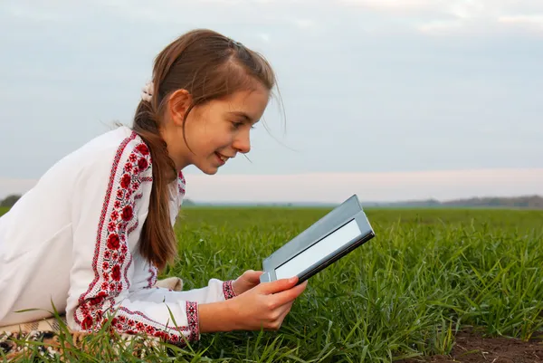 Chica adolescente con libro electrónico que pone en la hierba —  Fotos de Stock