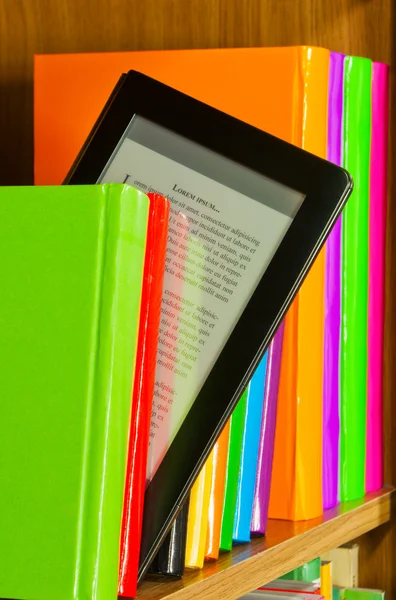 Raden av färgglada böcker och elektronisk boksläsare — Stockfoto