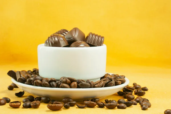 Tasse voll mit Kaffeebohnen und Schokoladenbonbons — Stockfoto