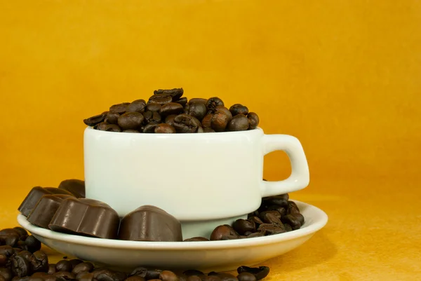Kuppi täynnä kahvipapuja ja suklaamakeisia — kuvapankkivalokuva
