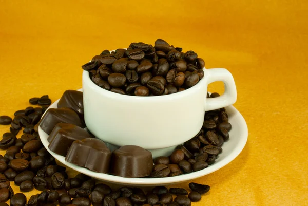 Ceașcă plină cu boabe de cafea și bomboane de ciocolată — Fotografie, imagine de stoc